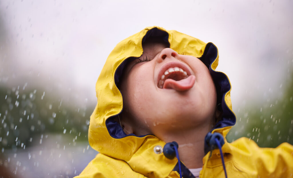 boy with mouth open to lick rain